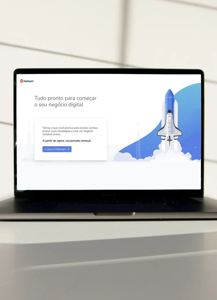 A laptop showing the Hotmart screen that closes onboarding, with a rocket taking off beside the next step.